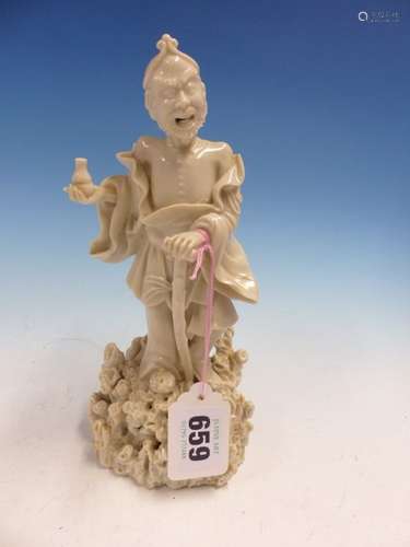 A BLANC DE CHINE FIGURE OF LIDIEHGUEI STANDING ON A ROCKY MOUND WITH A WALKING STICK IN HIS LEFT