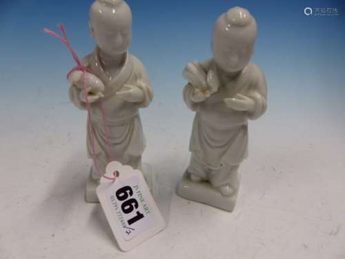 A PAIR OF BLANC DE CHINE FIGURES OF CHILDREN STANDING HOLDING FRUITS. H 12cms.