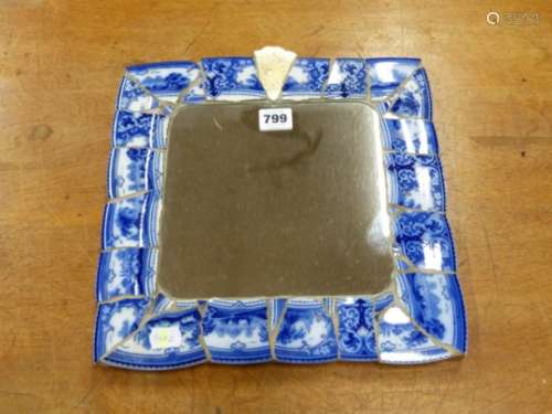 A SQUARE MIRROR IN A MOSAIC CERAMIC FRAME OF BLUE AND WHITE PRINTED PLATE RIM BANDS. 31 x 31cms.