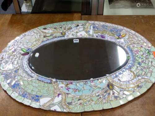 A BEVELLED GLASS OVAL MIRROR IN A FRAME OF MOSAIC CERAMICS FRAGMENTS, MIRRORED GLASS AND