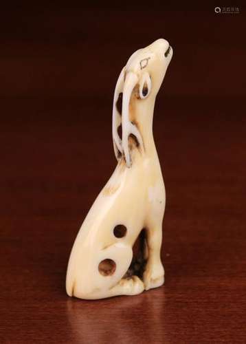 An 18th Century Kyoto School Ivory Netsuke carved in the form of a slender seated deer giving voice