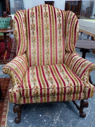 AN ANTIQUE GEO.I. STYLE WING BACK ARMCHAIR WITH CARVED WALNUT LEGS UNITED BY STRETCHERS.