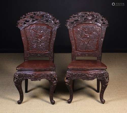 A Pair of Early 20th Japanese Chairs elaborately carved with birds & blossom and standing on