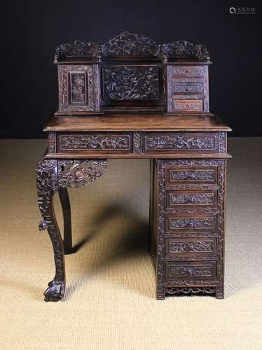 A 19th Century Chinese Export Writing Desk profusely carved with sprays of trailing prunus blossom