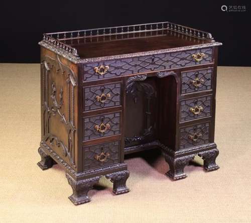 A Small Antique Kneehole Desk carved in the Chinese Chippendale Style with blind-fretted