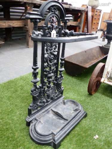 A CAST IRON STICK STAND, THE ROUND ARCH FLORAL BACK PANEL ABOVE REMOVABLE TWO COMPARTMENTAL TRAY.