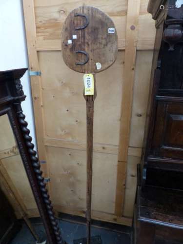AN ANTIQUE BREAD PADDLE MOUNTED STANDING ON IRON BASE.