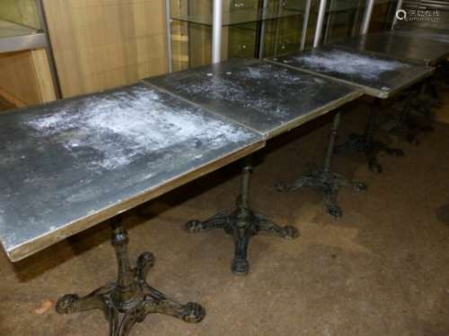 A SET OF FOUR VINTAGE CAFE TABLES WITH CAST IRON BASES AND ZINC WRAPPED PINE TOPS.