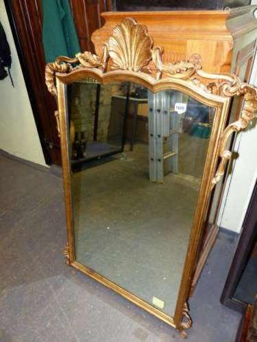 A VICTORIAN RECTANGULAR MIRROR IN A GILT FRAME THE SERPENTINE TOP CENTRED BY A SHELL BETWEEN FOLIATE