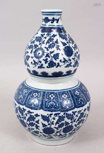 A CHINESE MING STYLE BLUE AND WHITE PORCELAIN DOUBLE GOURD VASE, decorated with formal scrolling