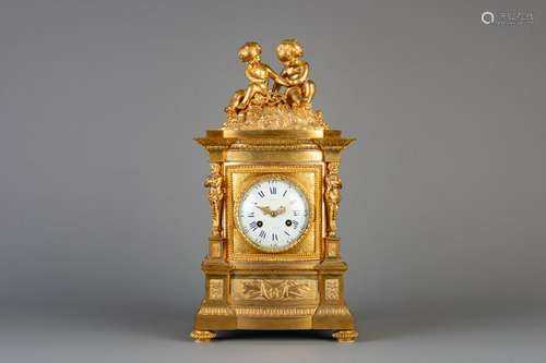 A gilt bronze mantel clock crowned with two putti and a