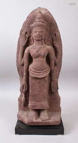 A 12TH CENTURY STYLE CAMBODIAN KHMER STYLE RED SANDSTONE CARVING OF A FOUR ARMED DEITY. 52cms high.