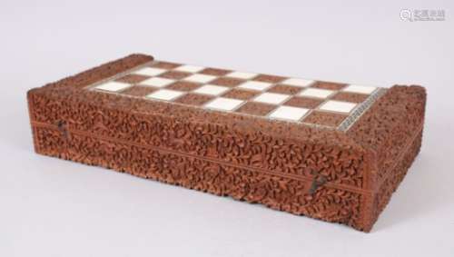 AN INDIAN CARVED SANDLEWOOD AND IVORY INLAID GAMES BOX with backgammon interior, 44cm long, 22cm