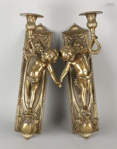 Two old brass candle holders with putti. In Louis Seize
