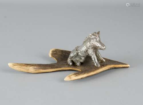 Plated miniature of a wild boar sitting on antlers.