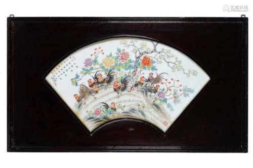 A polychrome porcelain fan shaped plaque in wooden frame, decorated with roosters, flowers and a