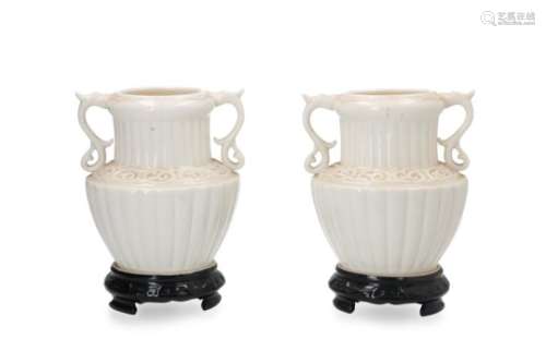 A pair of cream glazed porcelain vases with handles in the shape of a dragon. The bottom black