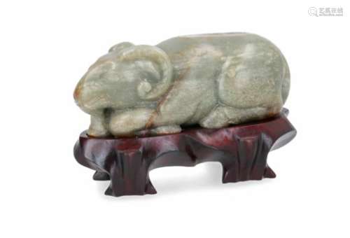 A jade and russet sculpture of a reclining ox, on wooden base. China. L. 14 cm. Provenance: bought