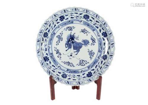 A large blue and white porcelain charger with scalloped rim on wooden stand, decorated with a qilin,