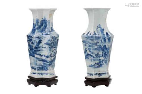 A pair of octagonal blue and white porcelain vases on wooden base, decorated with buildings in a