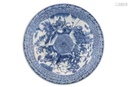 A blue and white porcelain charger, decorated with reserves depicting figures and animals. The