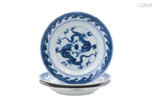 A set of three blue and white porcelain deep dishes, decorated with dragons chasing the burning