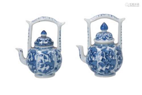 A pair of blue and white miniature teapots with pagoda shaped handles, decorated with flowers.