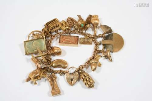 A 9CT. GOLD CURB LINK CHARM BRACELET with padlock clasp and suspending assorted gold charms, total