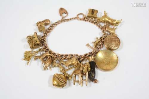 A 9CT. GOLD CURB LINK CHARM BRACELET with padlock clasp and suspending many assorted gold charms,