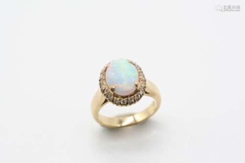 AN OPAL AND DIAMOND CLUSTER RING the oval-shaped solid white opal is set within a surround of