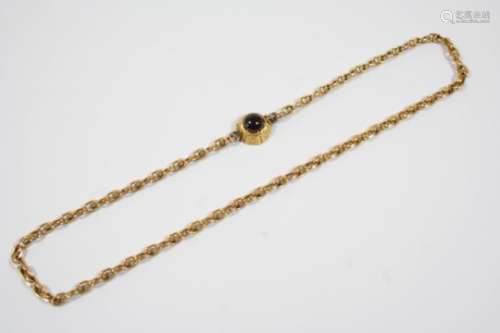 A GARNET AND GOLD CHOKER NECKLACE the circular cabochon garnet is mounted in a scrolling engraved