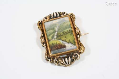 A SWISS ENAMEL AND GOLD BROOCH depicting a forest landscape with a lake and with mountains in the