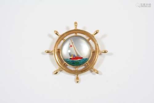 A REVERSE CARVED CRYSTAL INTAGLIO BROOCH depicting a ship's wheel, the intaglio depicting a yacht in