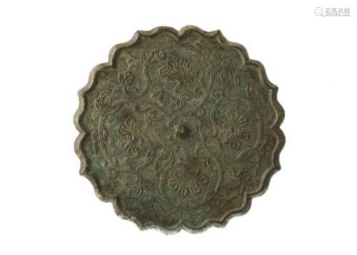 A bronze mirror with scalloped rim and relief decor of flowers. China, Tang. Weight approx. 861 g.