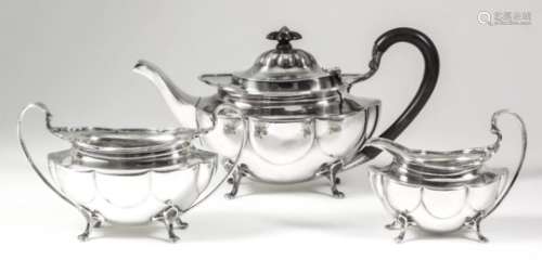 An Edward VII silver oval three-piece tea service of lobed form on four scroll feet, comprising -
