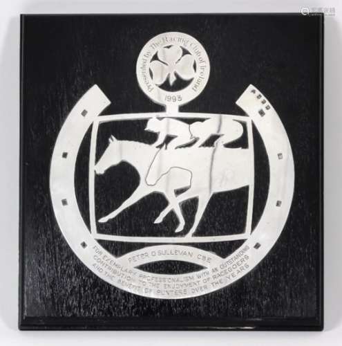 An Elizabeth II Irish silver presentation plaque in the form of two mounted jockeys within a