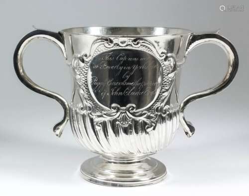 A George I silver two-handled cup, the bell shaped body embossed with oval cartouche with leaf