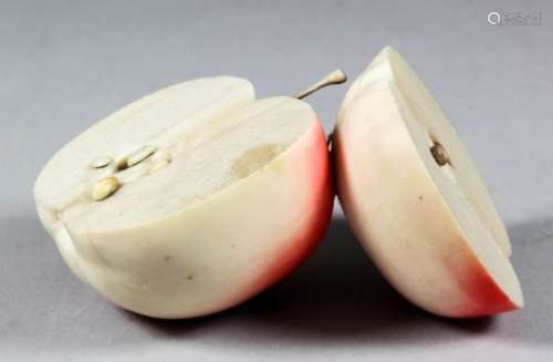 A Japanese carved ivory and red stained okimono in the form of a cut apple with textured cut surface