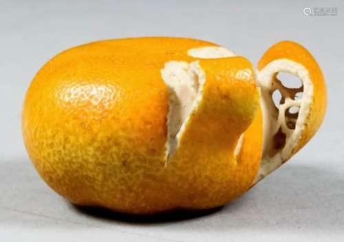 A fine Japanese carved ivory and orange stained okimono in the form of a partly peeled tangerine,