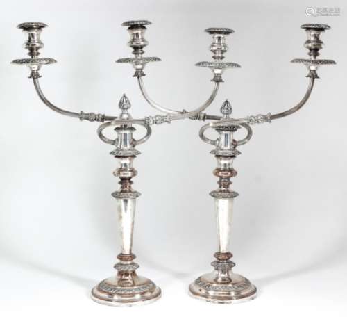 A pair of plated pillar candlesticks with two-branch candelabra fitments, with scroll cast mounts