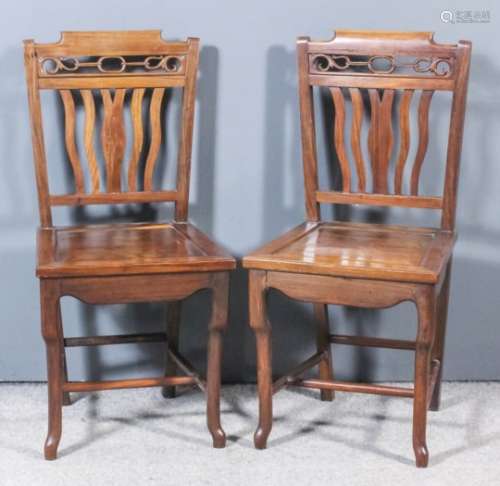 A pair of Chinese hardwood occasional chairs with shaped crest rails above fretted and carved