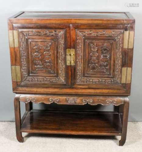 A Chinese panelled hardwood side cabinet, fitted one shelf enclosed by a pair of raised panelled