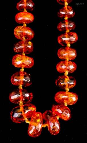 A single strand of seventy-four European reconstituted amber graduated beads of flattened circular