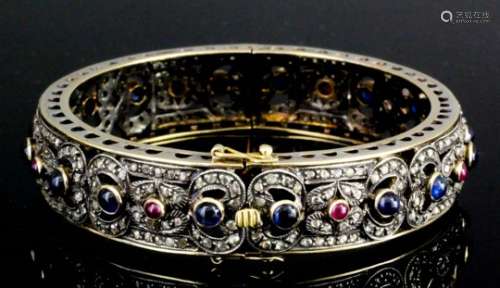A modern gold and silvery coloured metal mounted diamond, sapphire and ruby stiff bracelet by Damas,