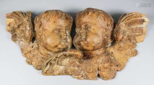 An 18th Century limewood carving of two winged putti heads, 20.5ins x 9ins high