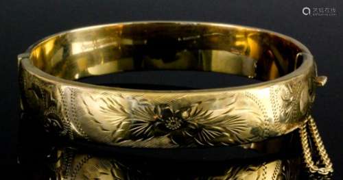 A 9ct gold stiff bracelet, the face engraved with floral leaf and scroll ornament, 16mm diameter (
