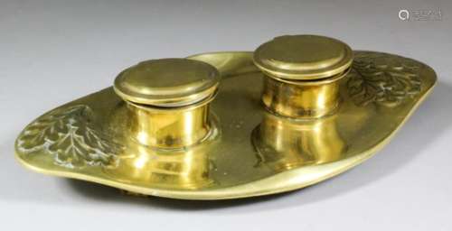 A German brass oval inkwell cast with oak leaves, and with two cylindrical inkwells, on panel
