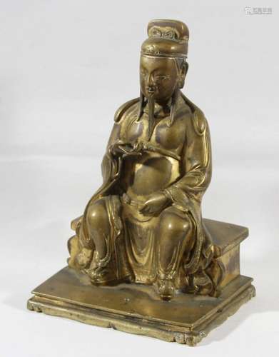 GILT BRONZE FIGURE OF A SEATED IMMORTAL, probably Chinese, the figure seated on a bench, height