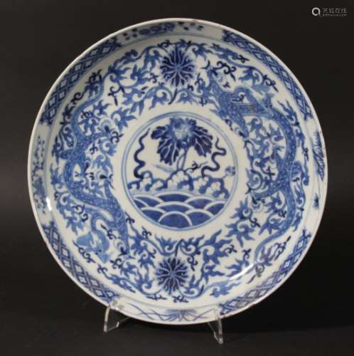 CHINESE BLUE AND WHITE SAUCER DISH, Kangxi marks but later, a central flower above waves, the border