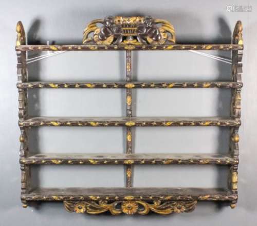 A carved wood and parcel gilt four-tier hanging wall rack, the whole carved with leaf and ribbon